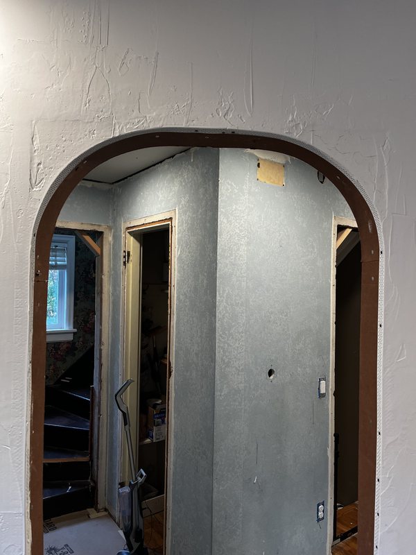 An arch with a beaded edge and the wall around it skimmed with rough plaster