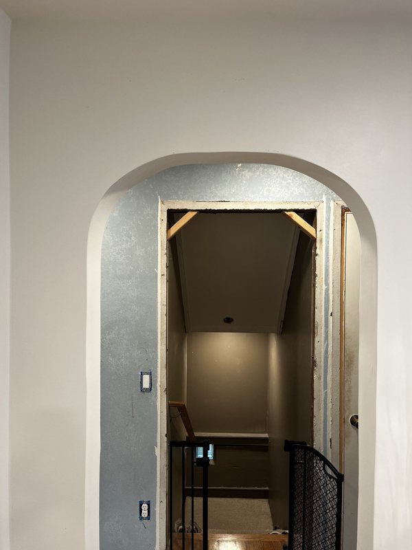 A finished arch, smooth and white, in a hallway wall